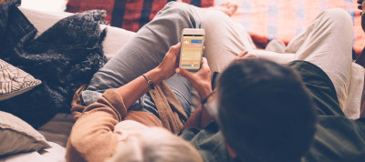 Man and woman on sofa with MELCloud app on smartphone