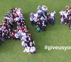 A++ sign made up of people standing together on the grass outside